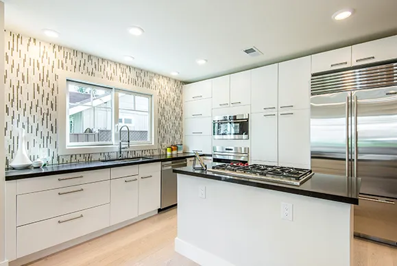 A modern kitchen with white cabinets, stainless steel appliances, and a dark granite countertop